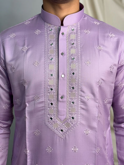 Close-up of a lavender embroidered shirt with intricate patterns on a plain background