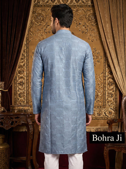 A man viewed from the back wearing a light blue patterned kurta with white trousers, standing in front of an ornate gold patterned tapestry. The brand name 'Bohra Ji' is displayed in a black box in the bottom right corner.