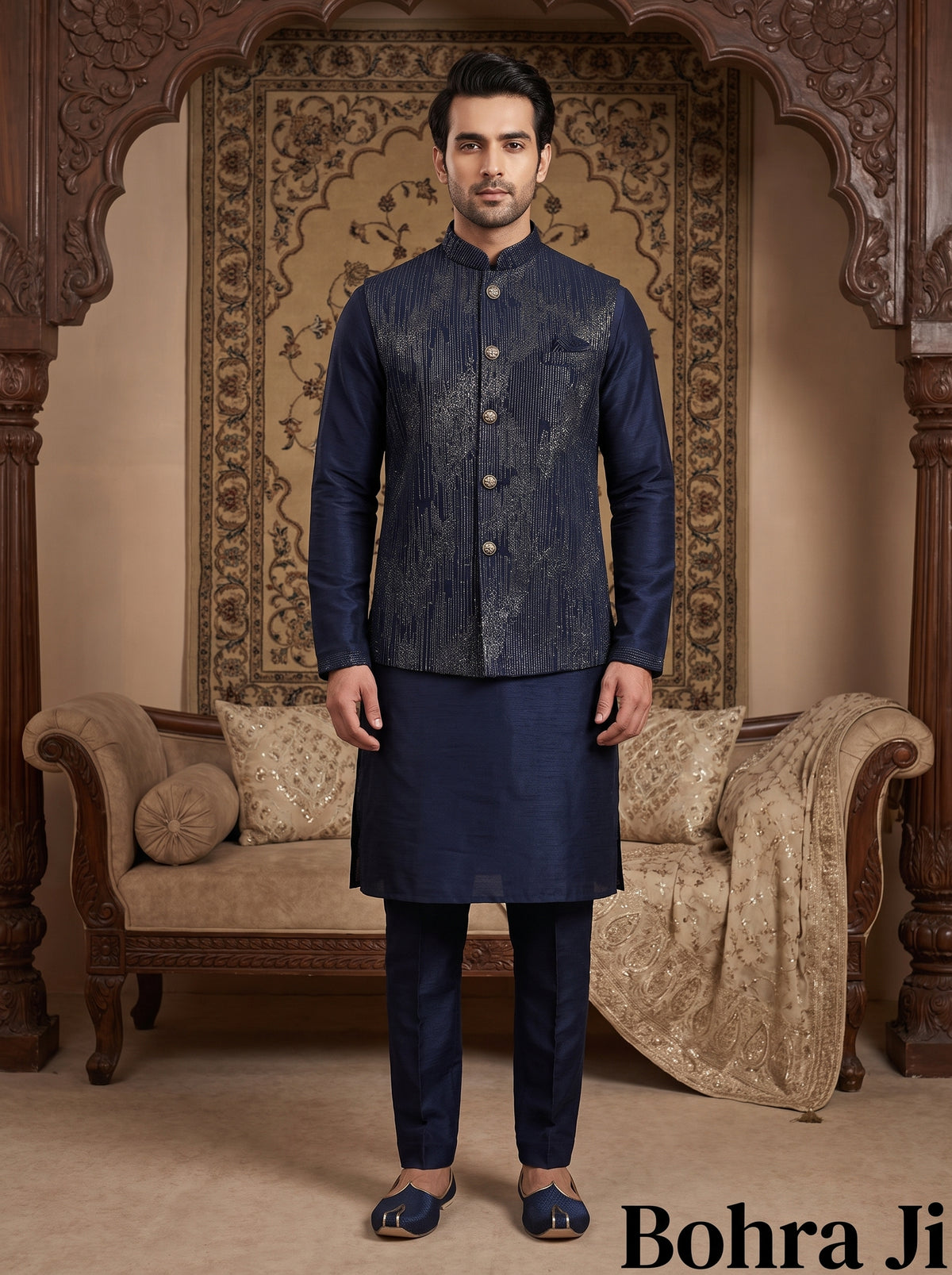 A man modeling a traditional Indian outfit consisting of a navy blue patterned waistcoat (kandha) and matching trousers (kurta and pajama set) in a richly decorated room with wooden arches and a patterned tapestry. The brand name 'Bohra Ji' is visible in the bottom right corner.