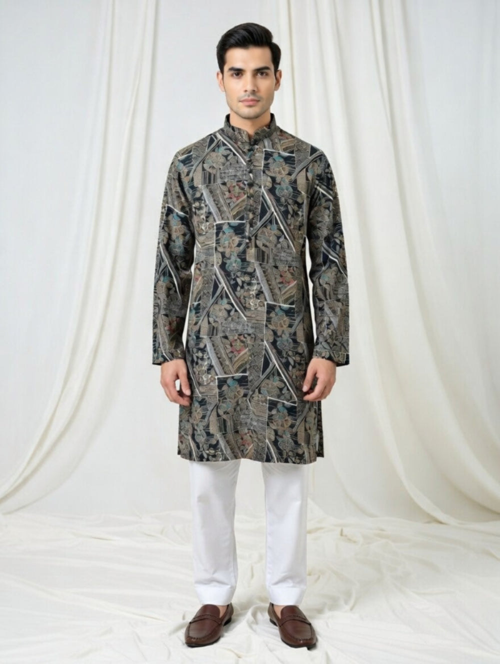 Man wearing a patterned kurta with white pants against a white curtain background