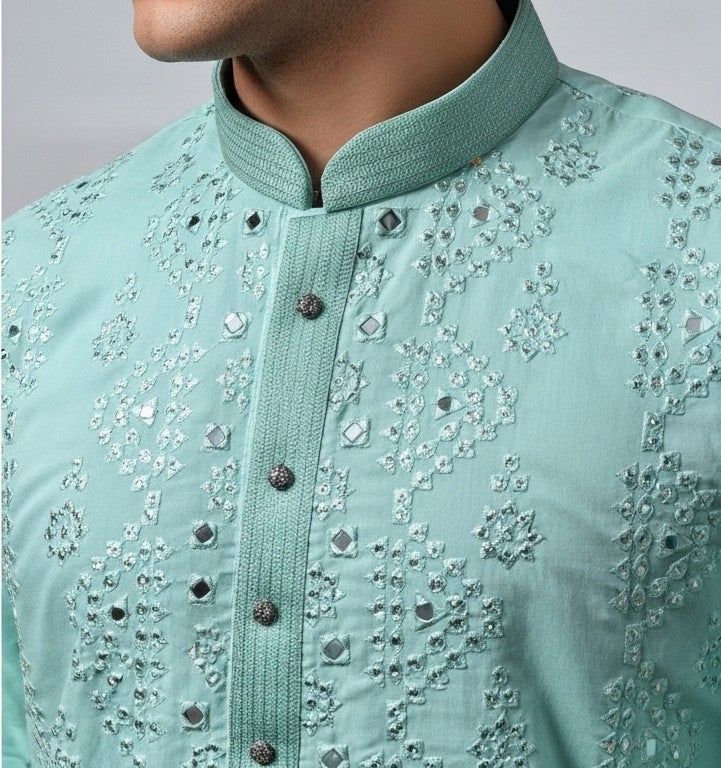 Close-up of a light blue embroidered shirt with intricate patterns on a plain background