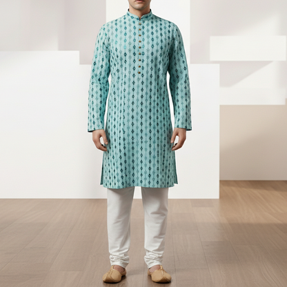 Man wearing a light blue kurta with white pants in a minimalistic room.