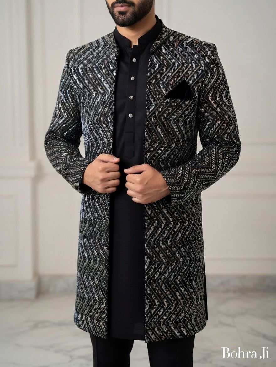 Man wearing a patterned coat over a black shirt against a neutral, open indo western jacket background. 