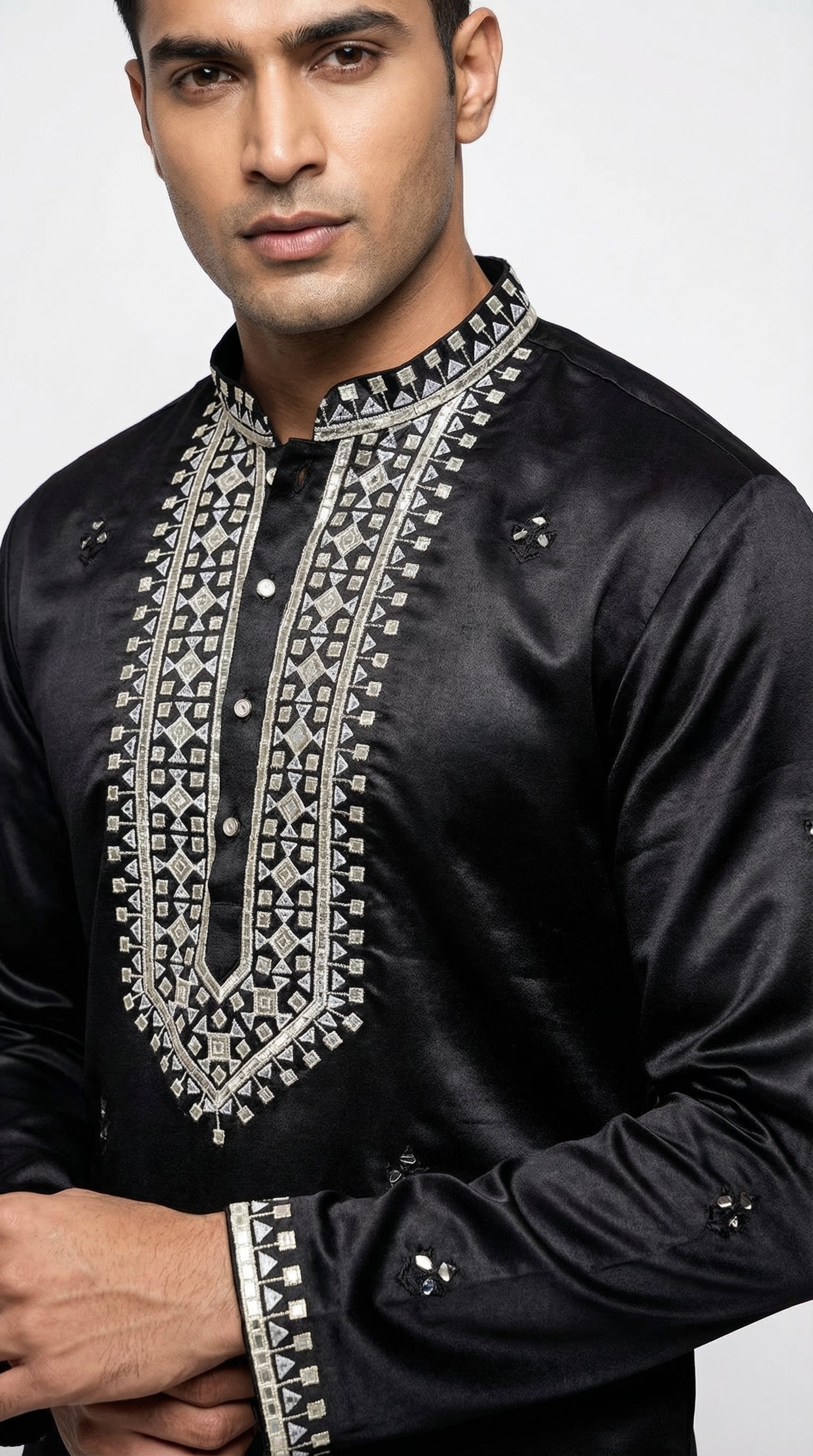Man wearing a black embroidered shirt against a white background