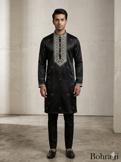 Man wearing a black embroidered kurta with pants against a neutral background