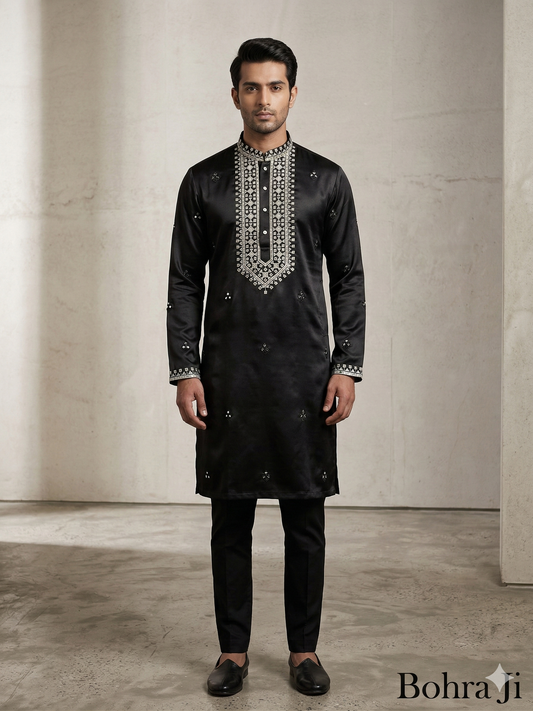 Man wearing a black embroidered kurta with pants against a neutral background