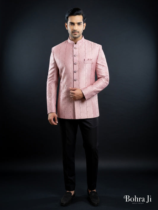 Man wearing a pink traditional jacket with black pants on a dark background