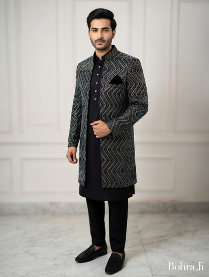 Man wearing a patterned black and gray traditional outfit against a white background